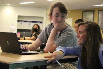 A student using a laptop with an instructor next to them.