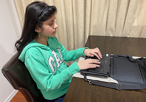 A student types on a braille keyboard.