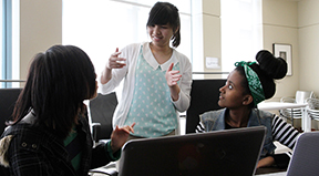 Three deaf students of color work on a computing project together