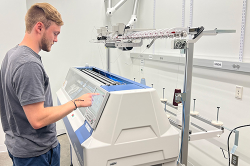 A student stands in front of a large piece of machinery.