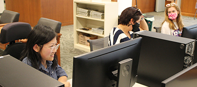 Students working on laptops in a library.