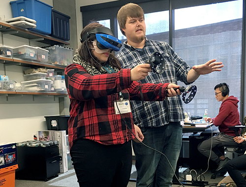 An instructor works with a student handling virtual reality technology.
