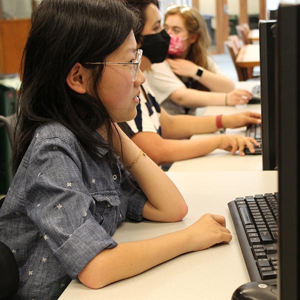 A student in a wheelchair sits with other students in a computer lab