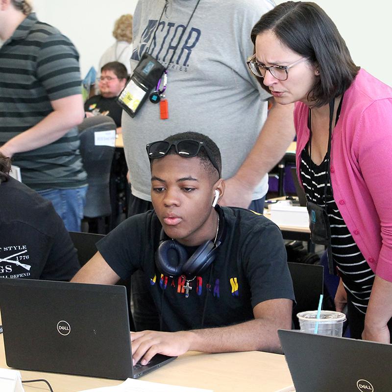 AccessCSforAll Leader Brianna Blaser working with a high school student who is using a laptop.